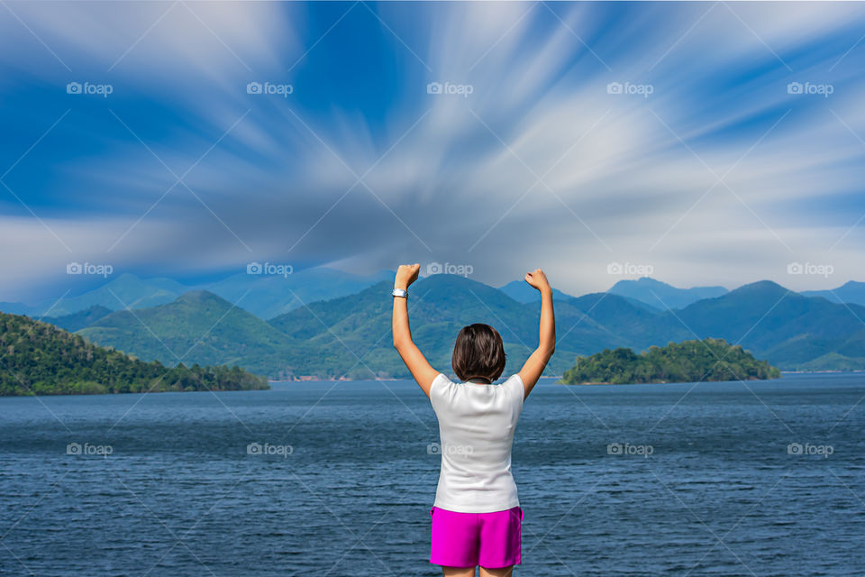 Women raise their arms at Kaeng Krachan Dam phetchaburi in Thailand and the clouds are flowing.