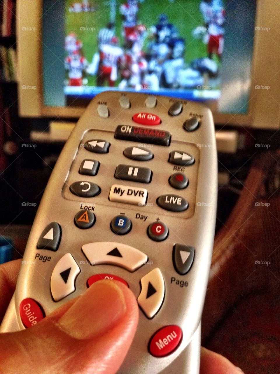 Person holding remote control while watching TV