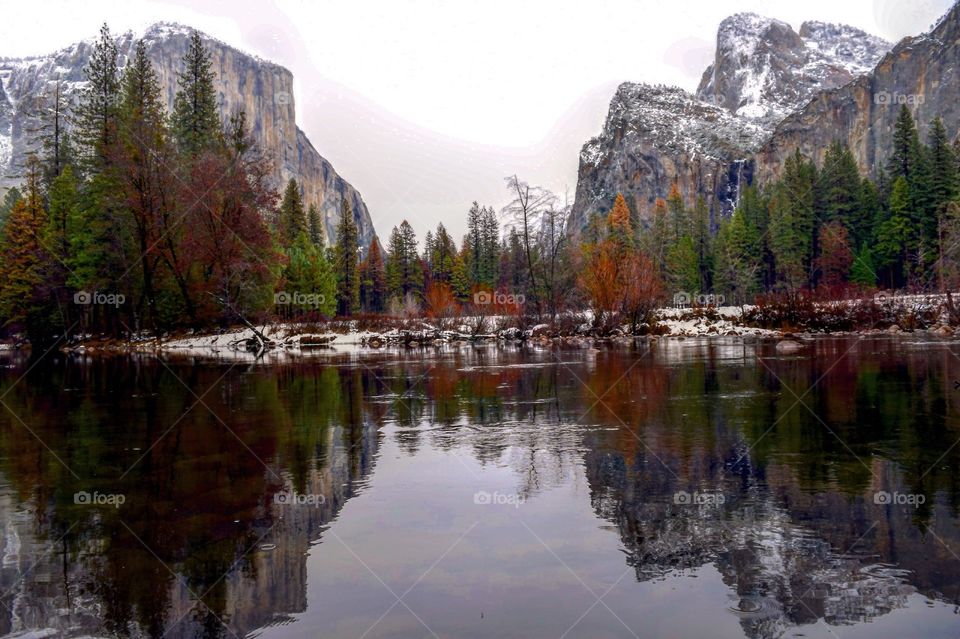 Rocky mountains and autumn trees reflecting on lake