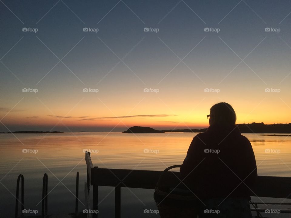 Woman with her back turned against the camera watching the sun go down