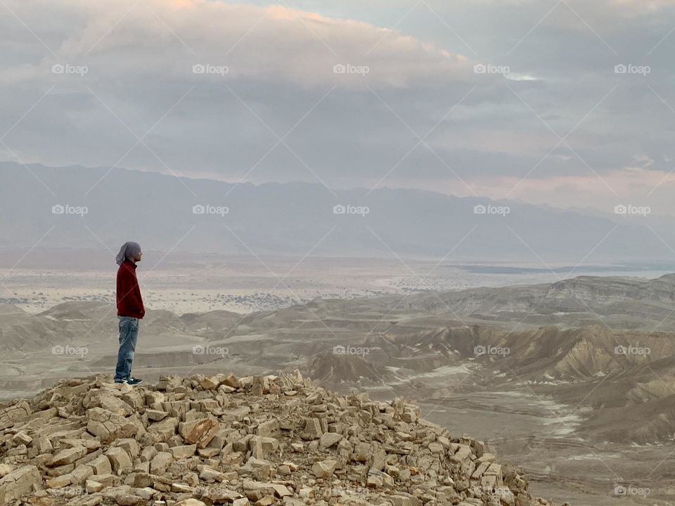 Man stand at the edge of the cliff looking the view and sunset colors 