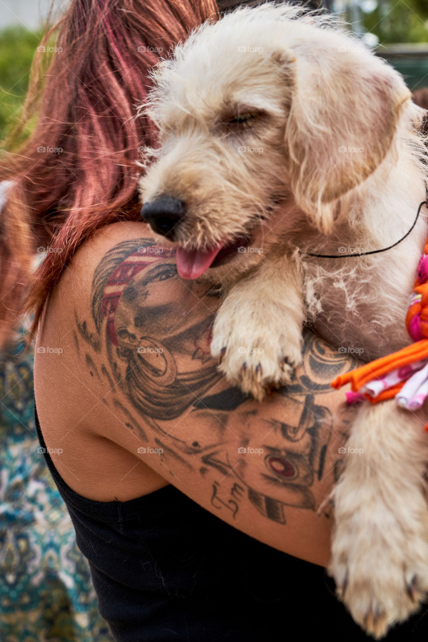 Tattoo arm of a woman holding a cute puppy.
