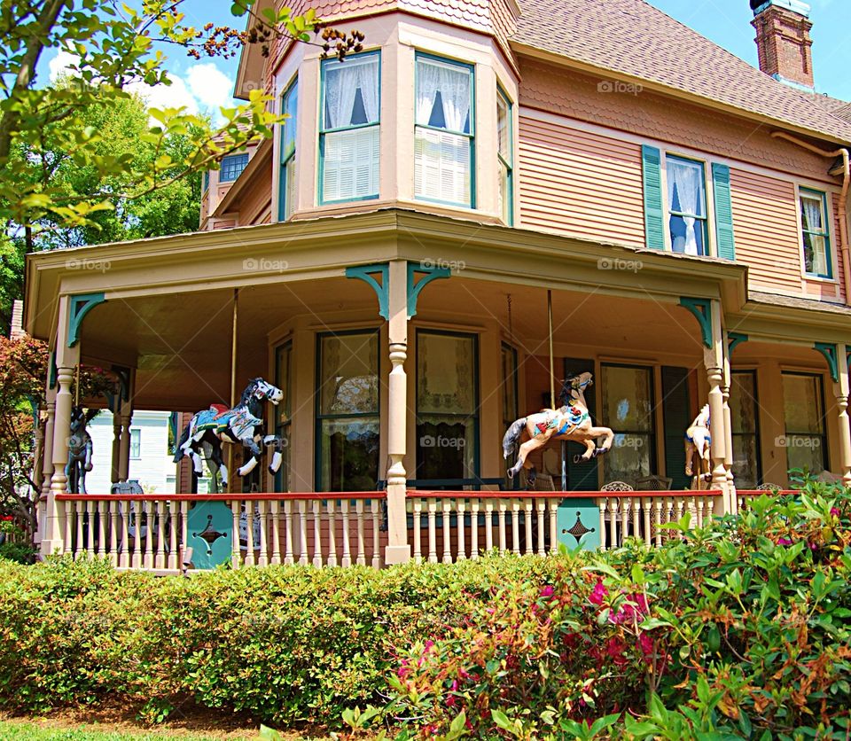 Victorian house with carousel horses on porch