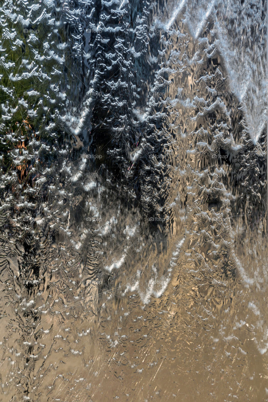 Stream of water and reflection in metallic fountain in Cardiff, Wales
