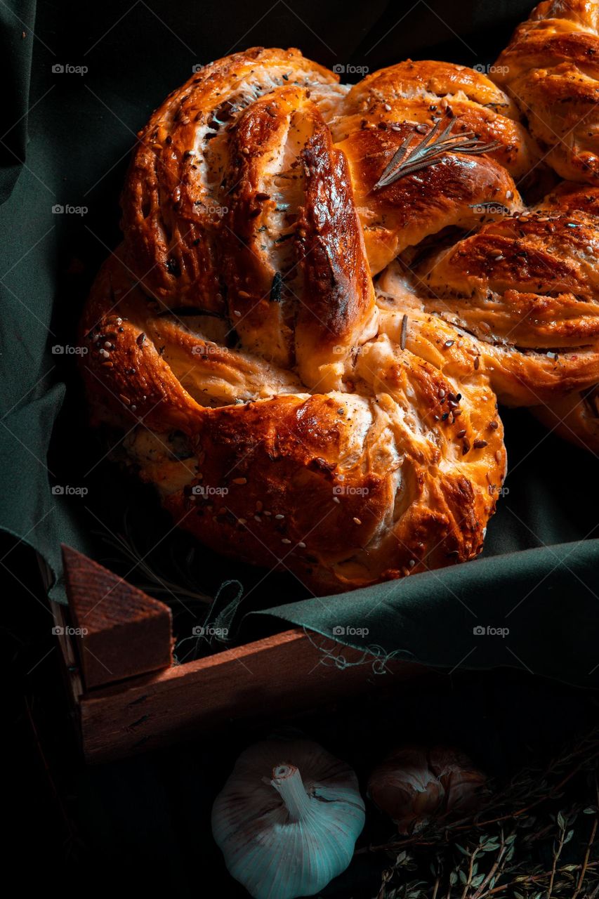 Rosemary twisted loaf bread on a green wooden background, still life, rustic style.