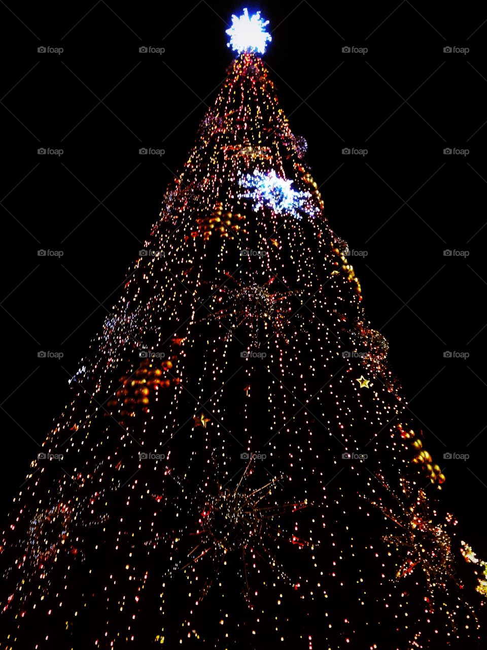 Bright colored illumination on artificial Christmas fir tree in the evening on black sky background in Moscow, Russia