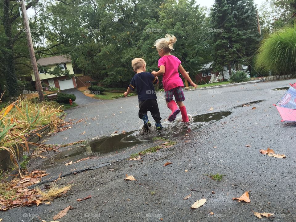 Children jumping in rain puddles in the street.
