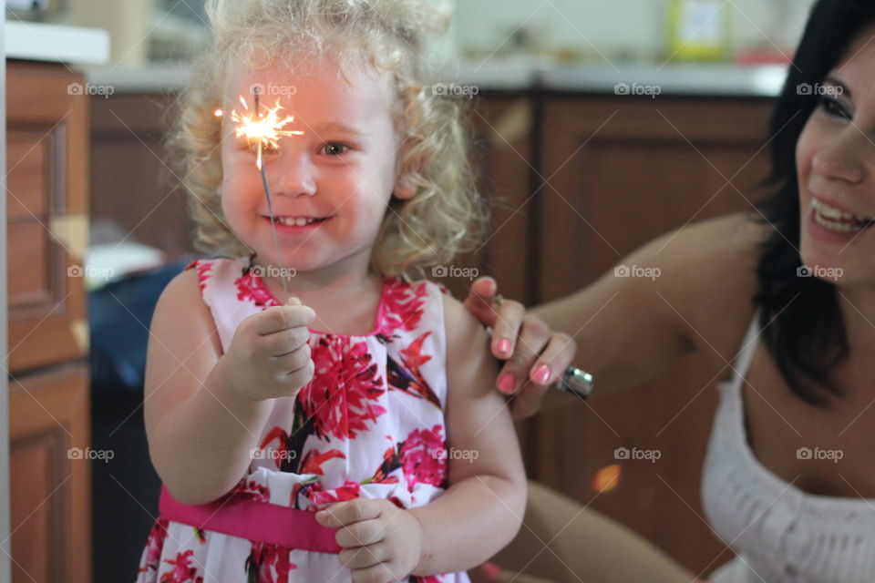 Smiling daughter holding sparkler