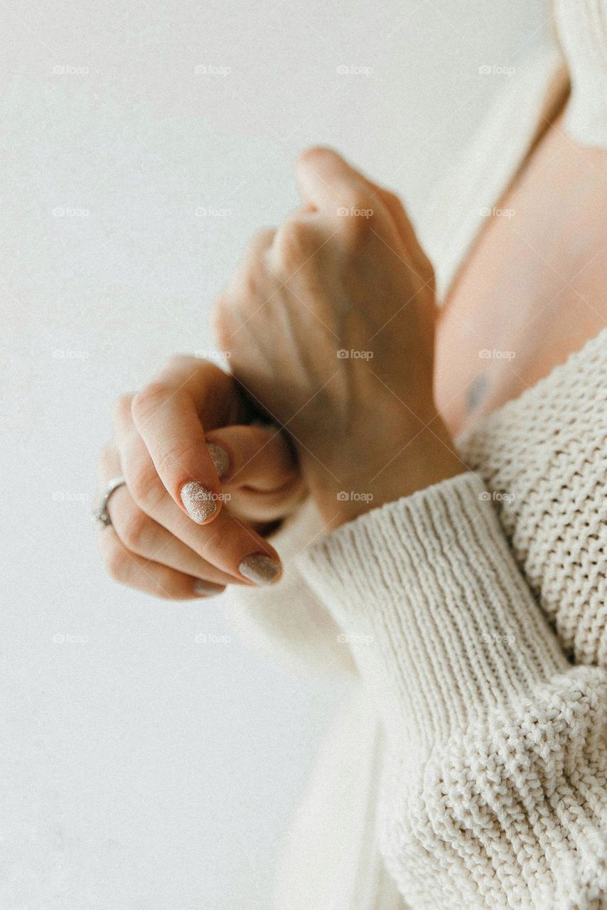 Girl in white coat holding hands with shine manicure on white background