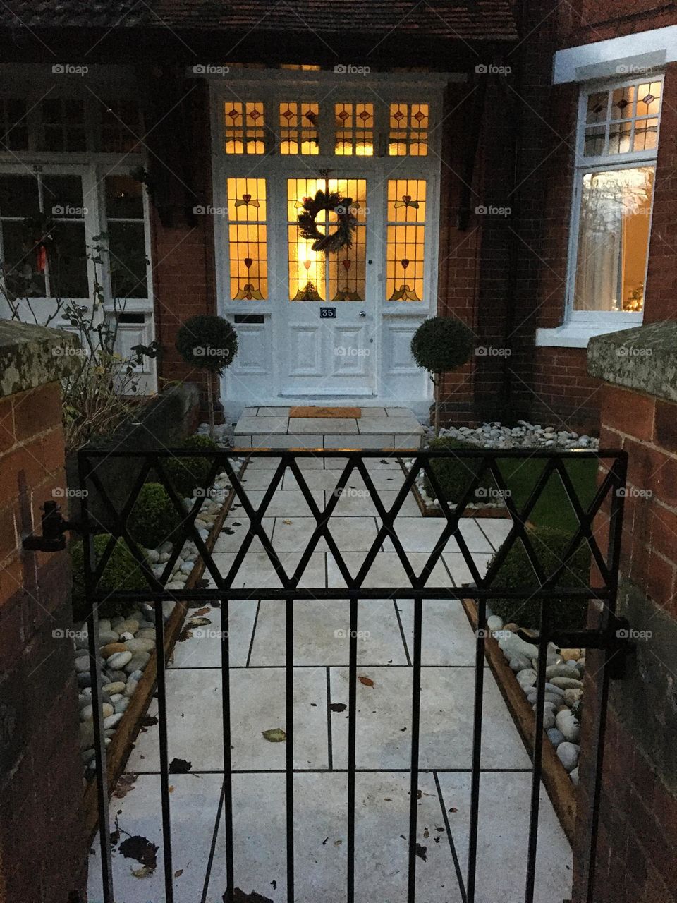 Old Victorian Terraced House decorated with a Christmas Wreath … light on in the hallway … 