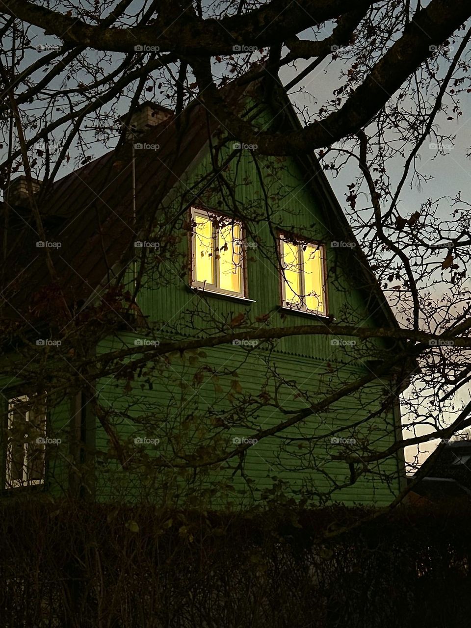 Scary green dark house with two illuminated windows 