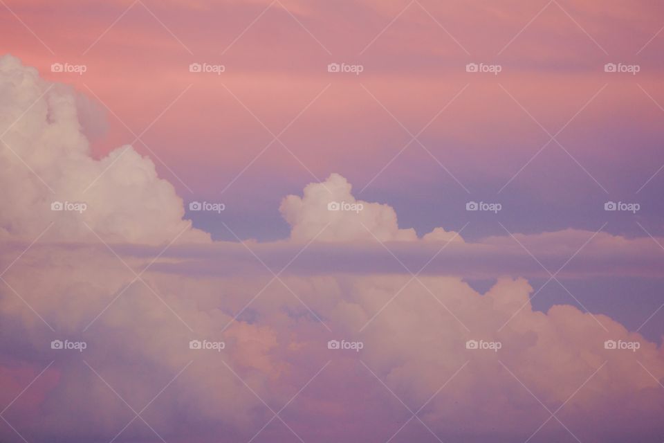 A thin stratus cloud in front of expanding cumulonimbus clouds against a beautifully painted sky 