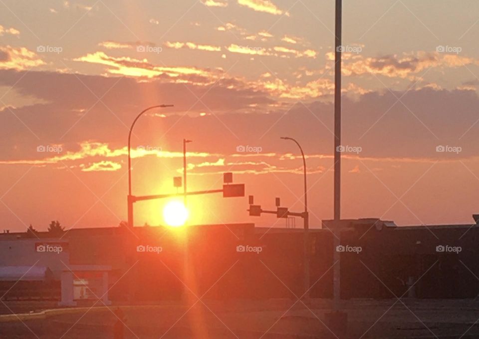 Brilliant and beautiful yellow, orange,red, colorful sunset in a small city, behind the traffic lights at an intersection 
