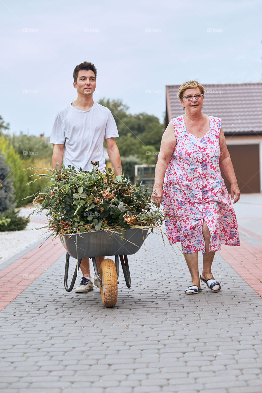 Grandchildren helping grandmother at a home garden. Candid people, real moments, authentic situations