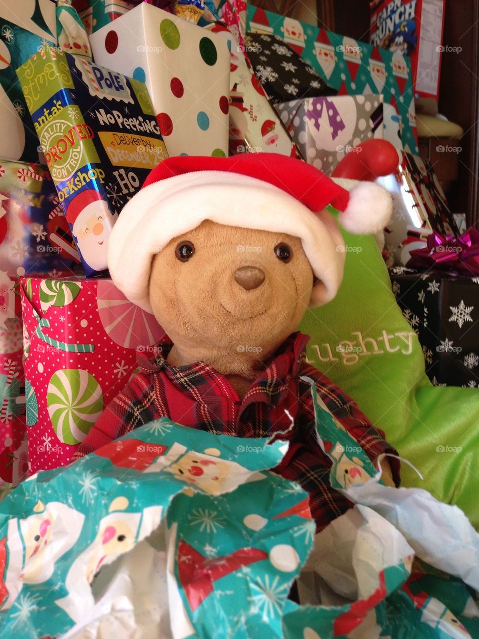 Teddy bear surrounded by Christmas presents and wrapping paper