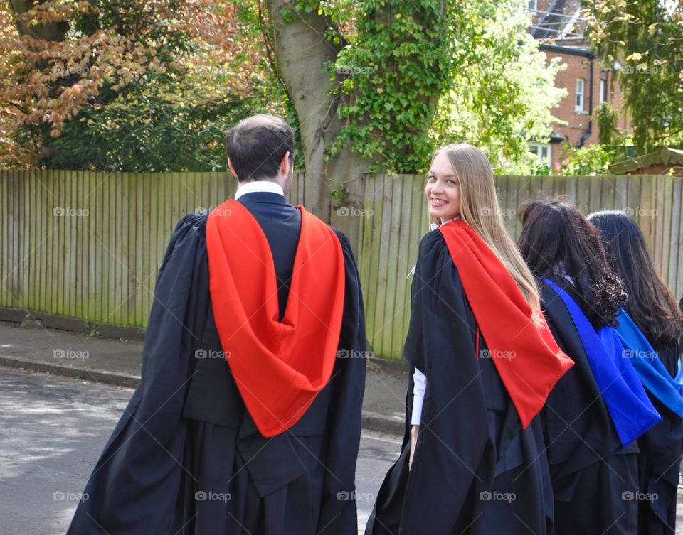 Group of students walking on street wearing graduation gown