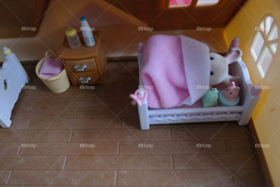 baby girl bunny snuggling under a pink blankie in her crib for bedtime