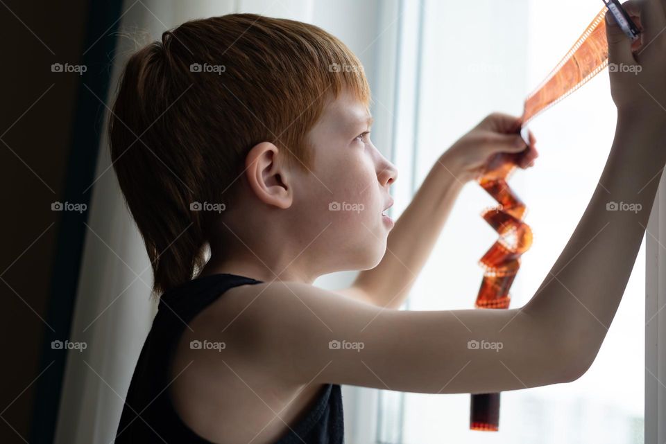 Red hair boy looks at the window and photo 