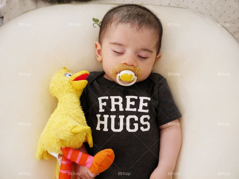 Elevated view of a baby sleeping with pacifier in his mouth