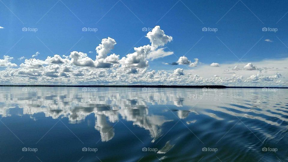Uma paisagem de águas com o céu azul nublado.