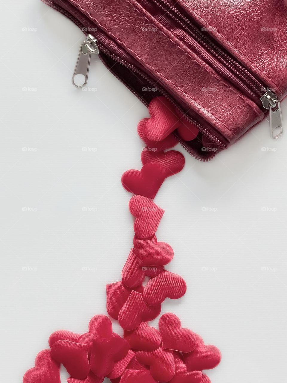 A purse/pocket/pouch pouring love hearts against a white background 