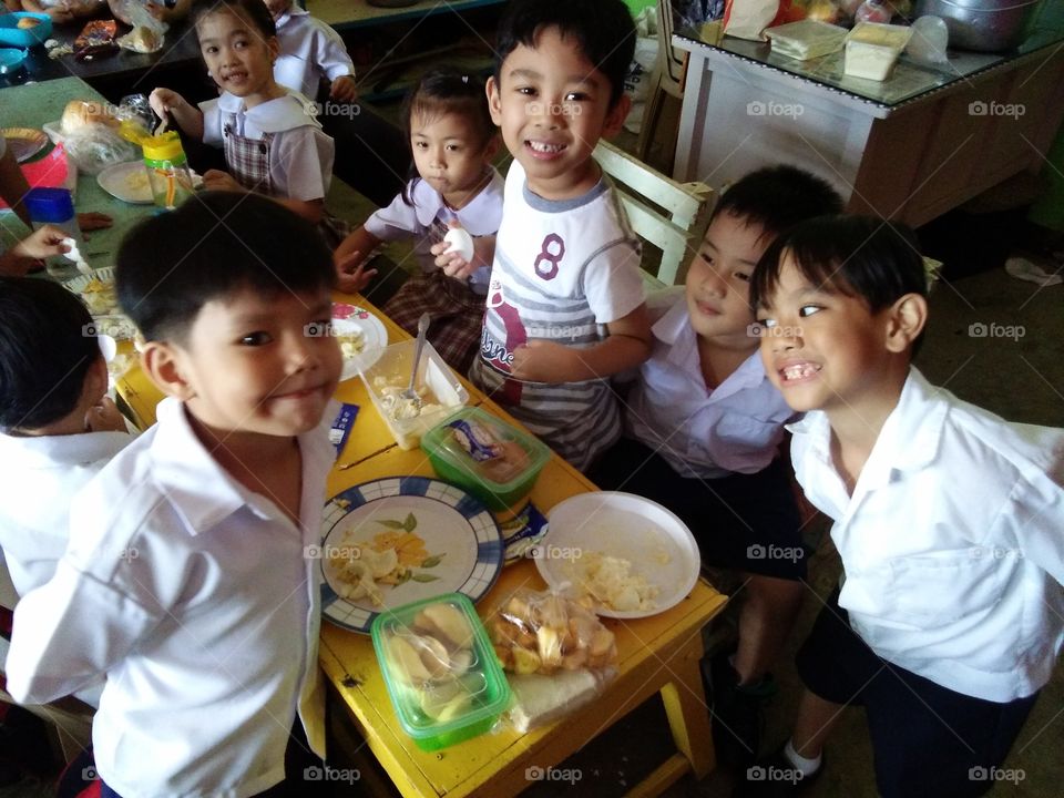 School children sitting on table eating lunch