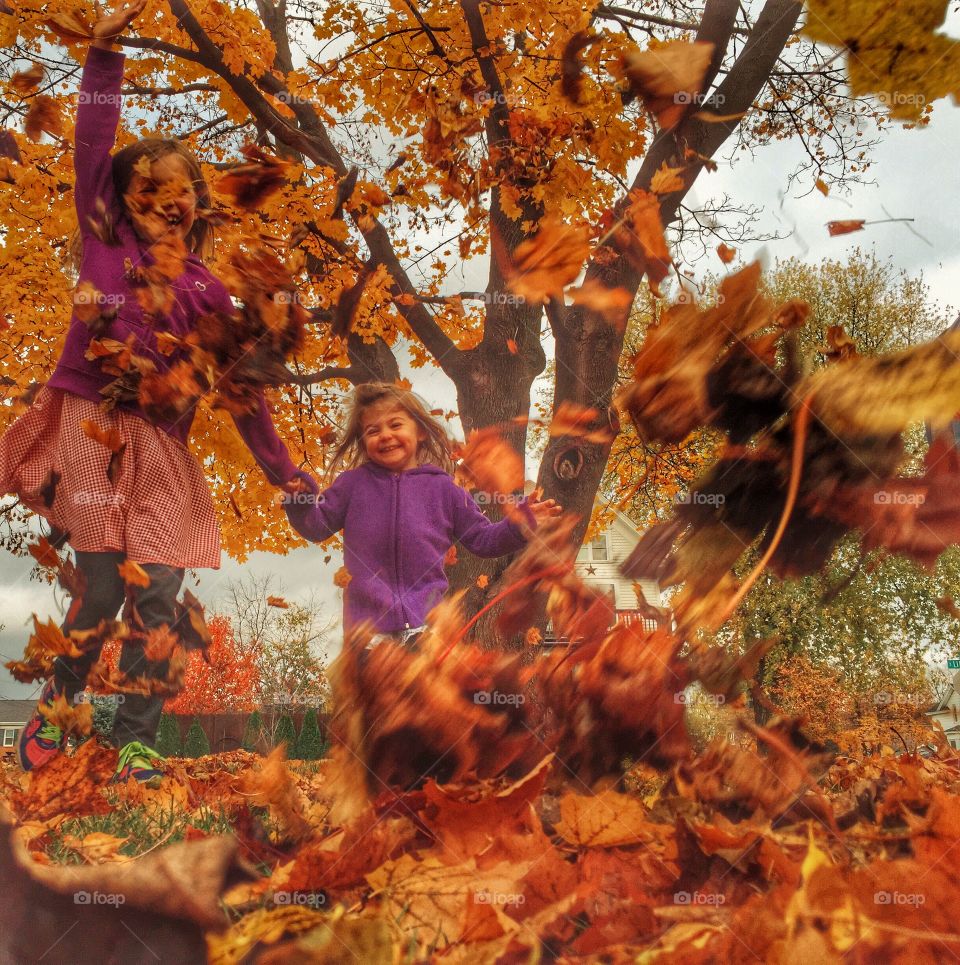 Two girls playing in autumn leafs