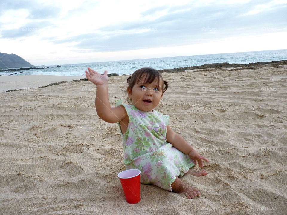 Baby having fun and saying hello at the beach