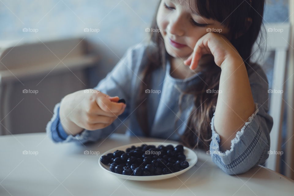 Girl with blueberries at her breakfast 
