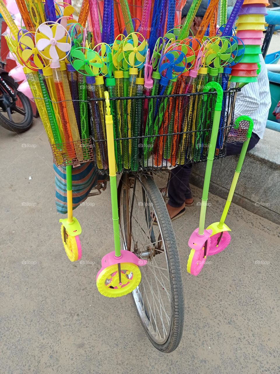 man carrying plastic toys for sale on bicycle