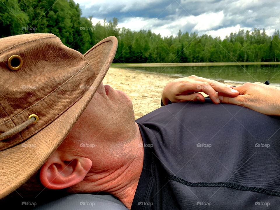 Man asleep on beach with hat covering face