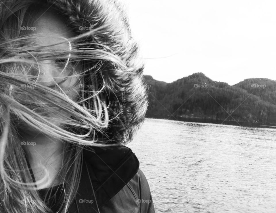 Woman standing at lake side with her hair swept by wind
