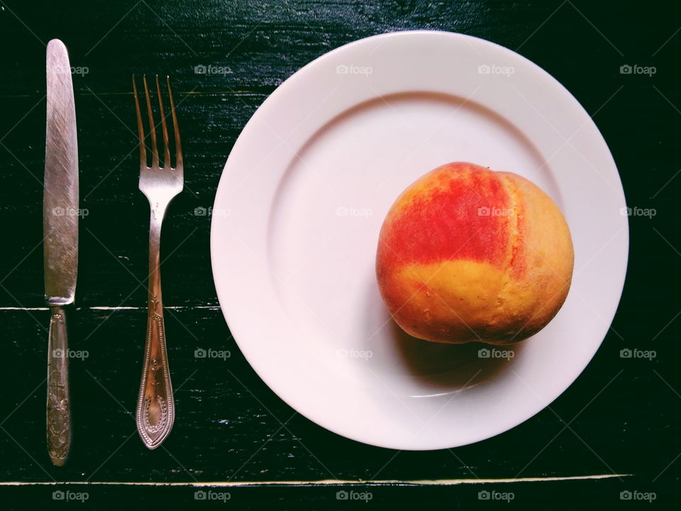 peach is lying on a plate with a fork