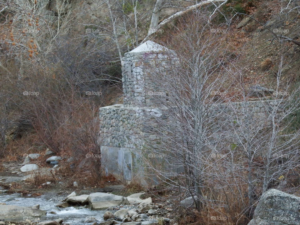 Old, broken stone incinerator next to a runbing stream.