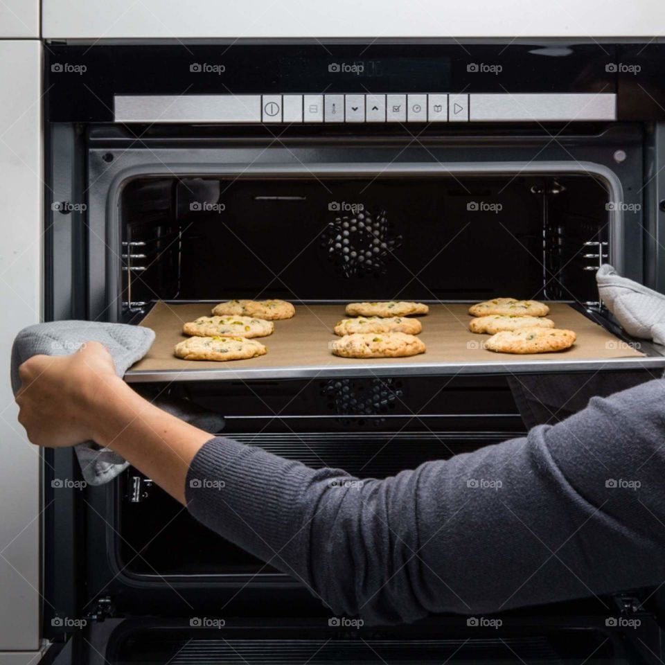 Woman taking out baked cookies from oven