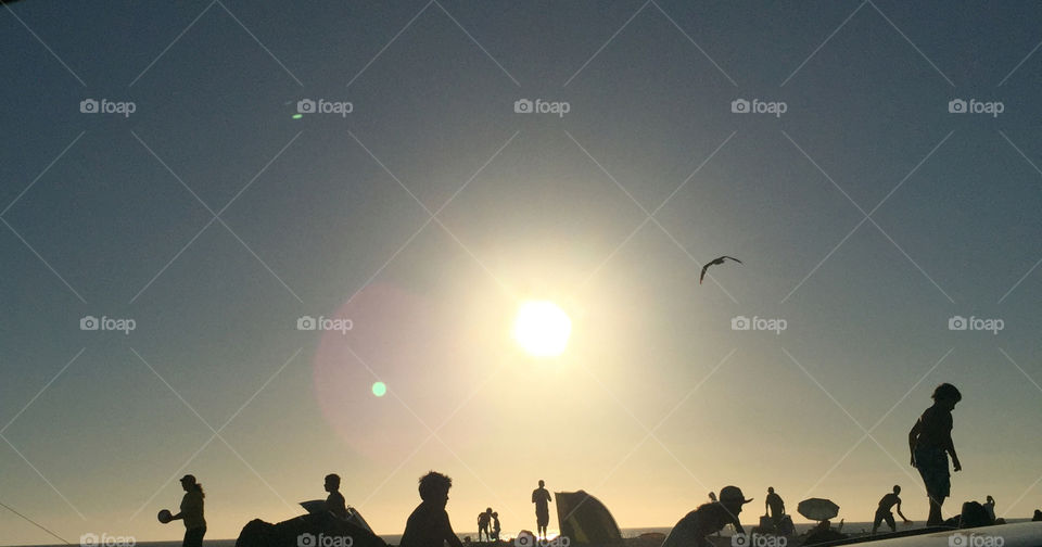 Sun setting over Beachgoers. Pacific Ocean. The beginning of the setting sun as people on the beach play. 