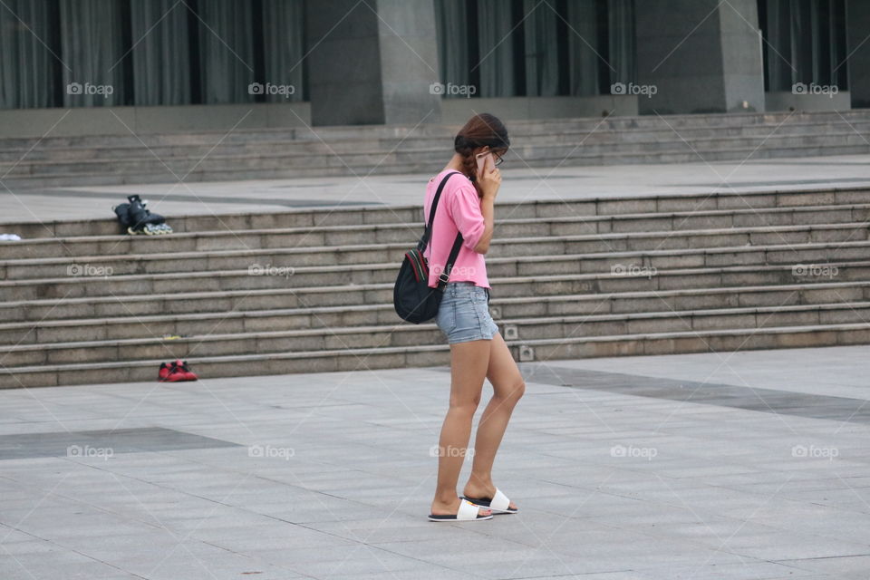 A Beautiful Girl is Talking Over A Phone and Walking