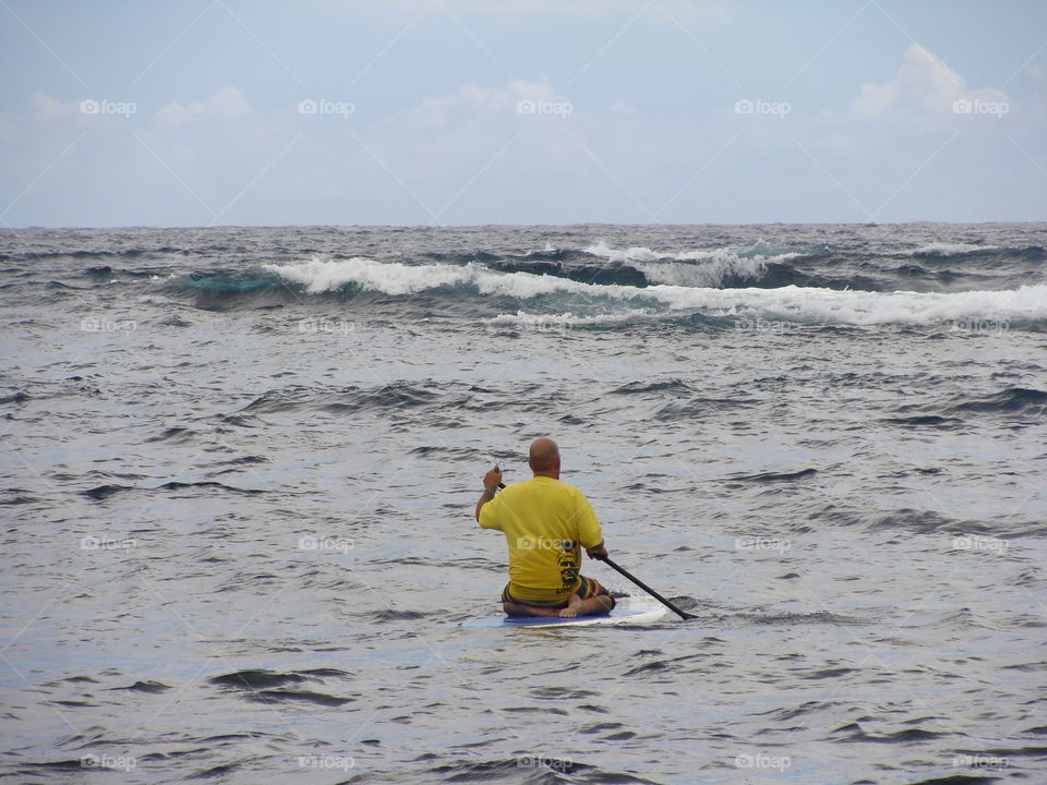 Paddle boarding. Out into the ocean he goes.