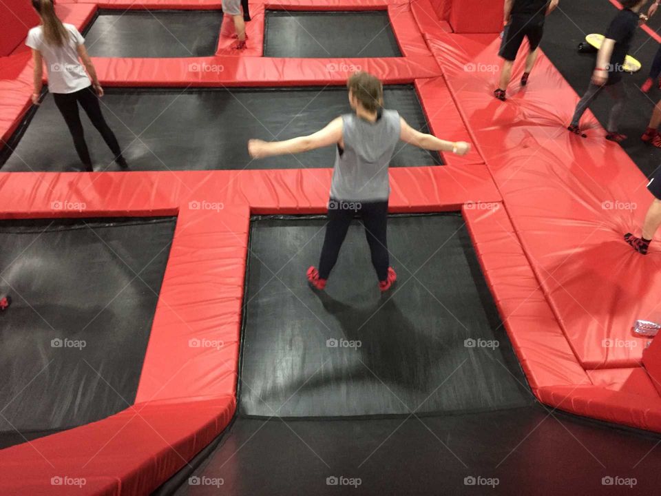 A girl jumping on a trampoline in a trampoline park
