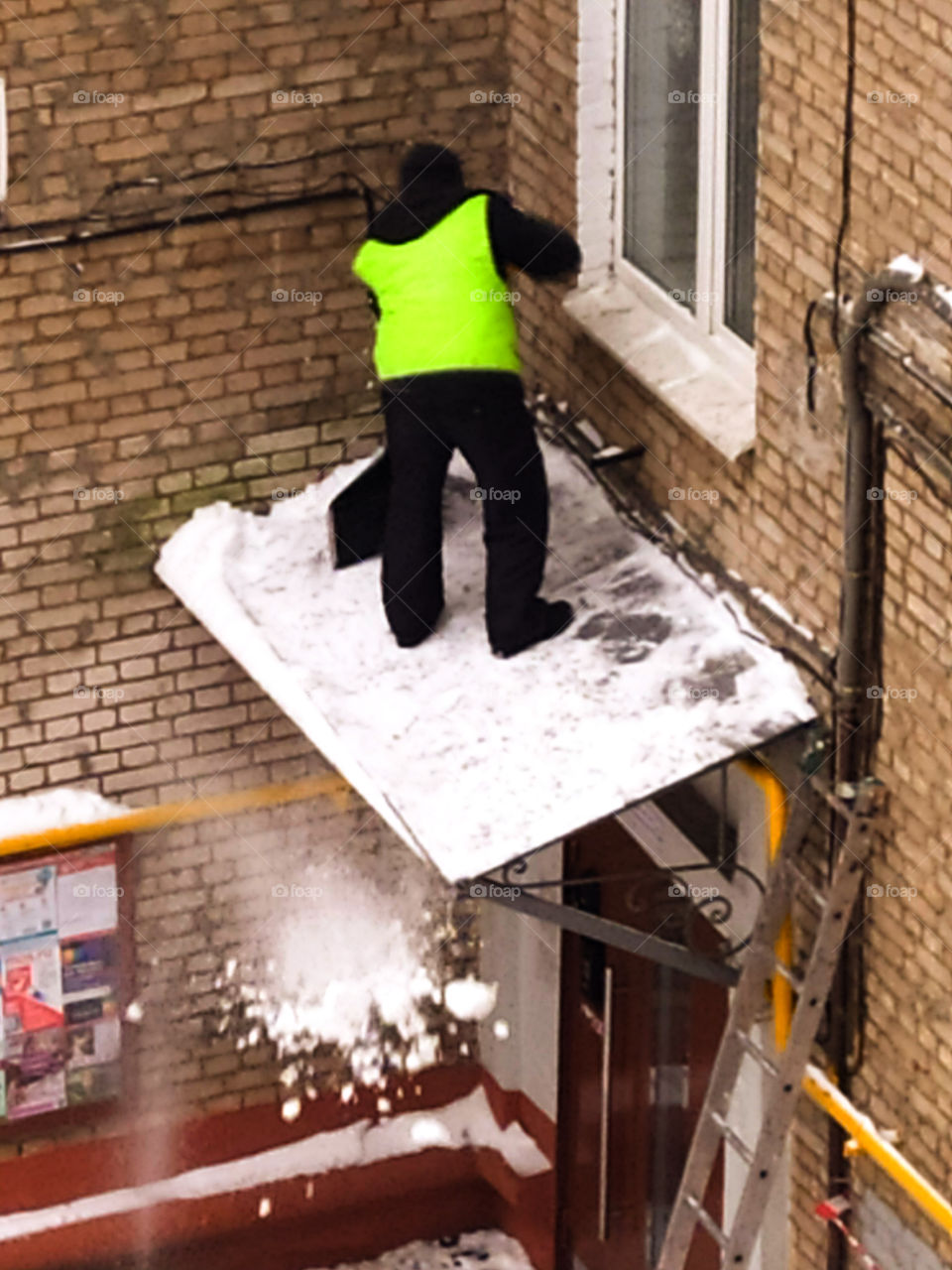 Man in uniform shovel snow from the roof