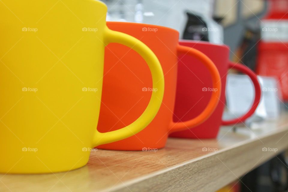 several mugs on the bar. yellow, red and orange mugs