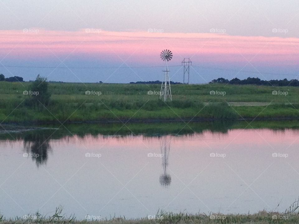 Iowa sunset. Windmill on the pond
