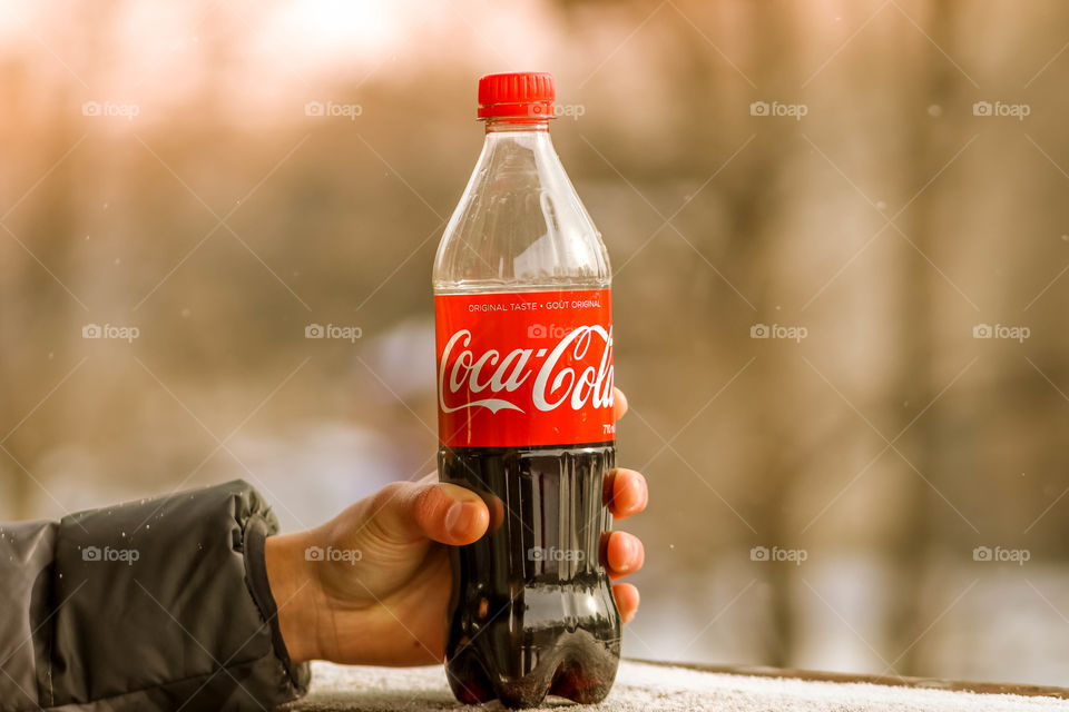 Hand holding a bottle of coca cola