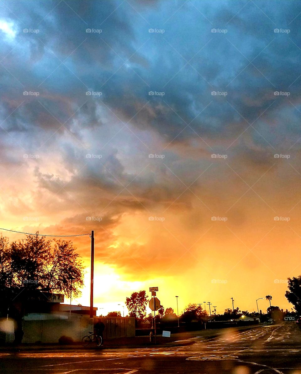 Splendor of yellow sun setting while menacing storm clouds approach