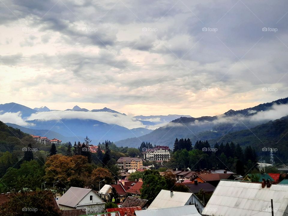 Overcast sky looming over small town in mountains, early autumn colors and low cloud cover
