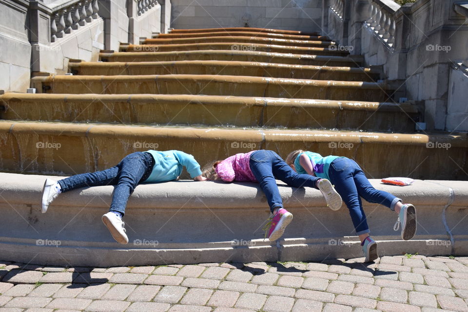 3 Little Girls, 1 Giant Fountain. Girls trying to reach the cold water on a spring day