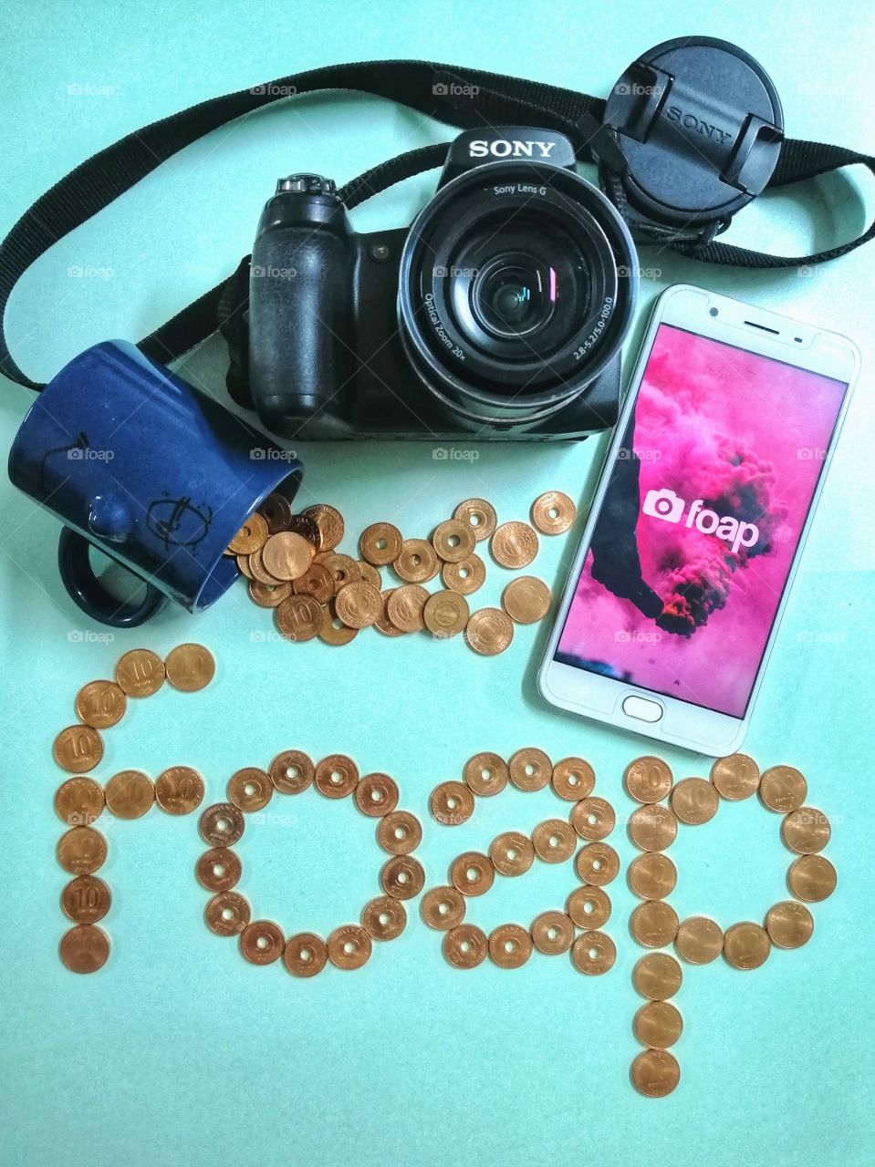 A picture that shows the foap word formed with coins and a mobile phone and a digital camera that shows you can earn money with your photos.