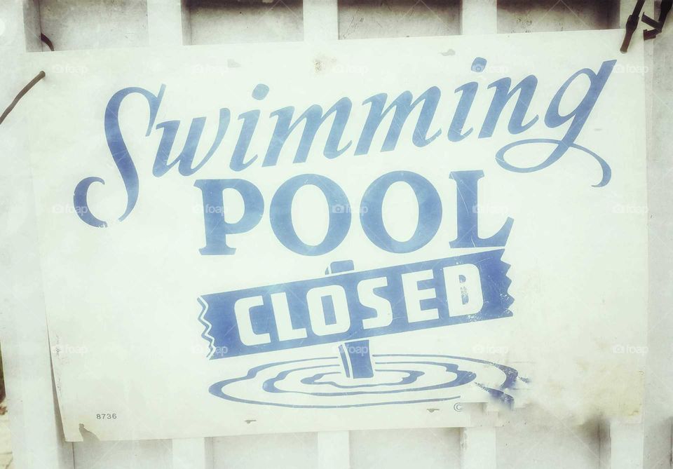 White out sign on gate says swimming pool closed