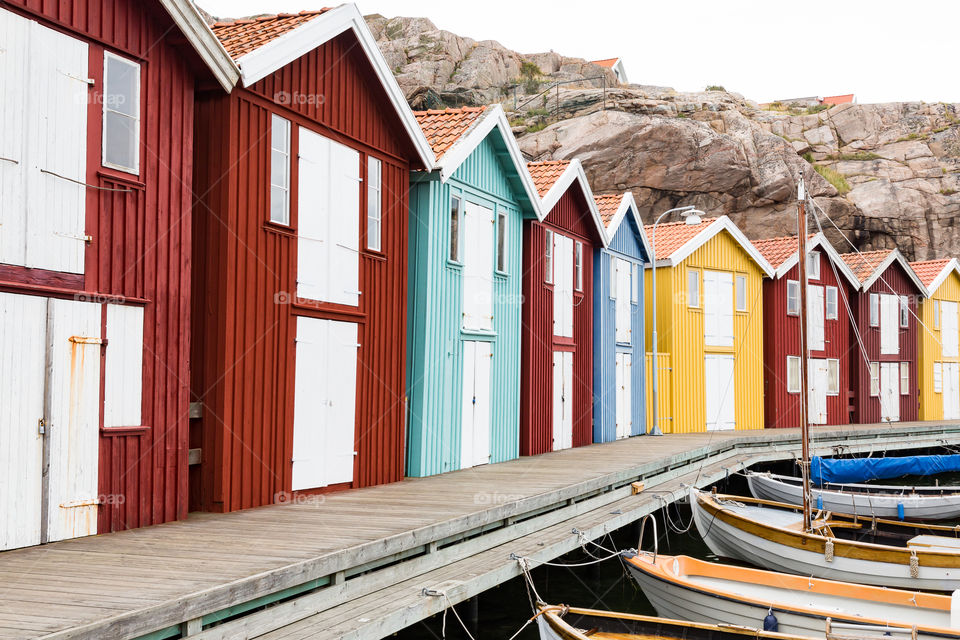 Colorful boathouses along wooden pier, mostly red houses 