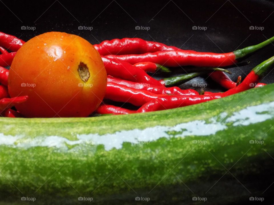 Tomatoes, red chilies and cucumbers on a frying pan